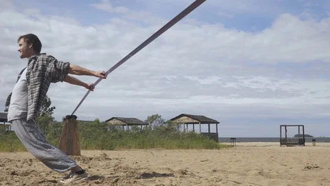 Young man Balancing and jumping On A Slackline At Sea Shore Sand Beach Healthy Видео 91251733