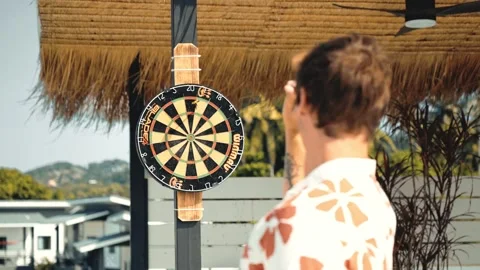 Young man on the balcony playing darts in tropical paradise in Thailand. Vidéo 334672139