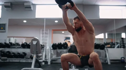 The young man, with a bare chest, performs a dumbbell exercise in the gym Stock Footage 156480757