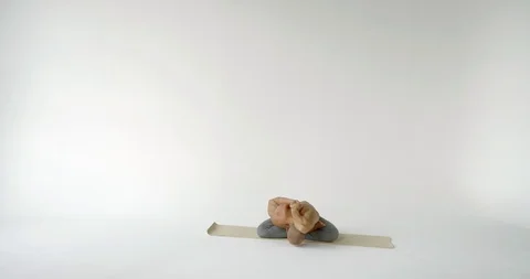 Young man with bare torso bends in gomukhasana sitting in lotus pose on mat in Video stock 119359142