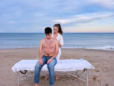 A young man with bare torso sitting on a massage table receiving a chiromassage Stock Photos