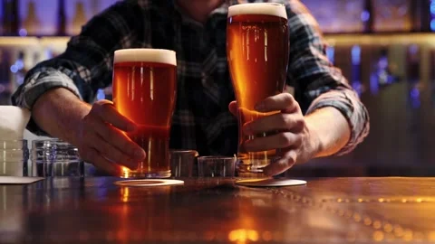 Young man, bartender serving two glasses of chill lager beer at bar, pub Stock Footage 243676300