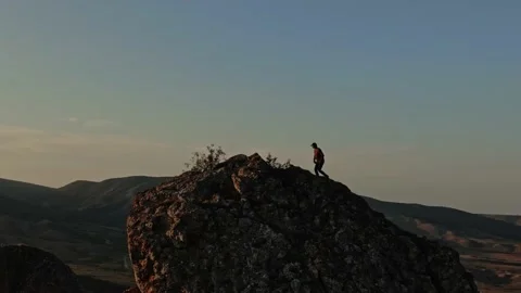 A Young Man in a Baseball Cap Climbs the Top of the Mountain Stops and Makes Vic Stock Footage 150593052
