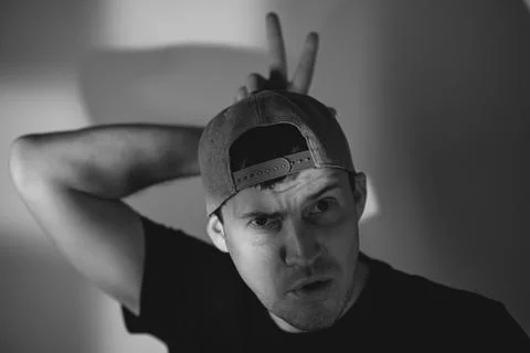 Young man in baseball cap making bunny ears gesture over head. Portrait of pl Stock Photos