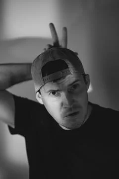 Young man in baseball cap making bunny ears gesture over head. Portrait of .. Stock Photos