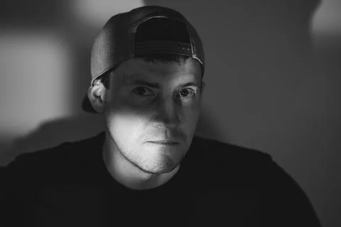 Young man in a baseball cap posing for a portrait. Dramatic lighting with s.. Stock Photos