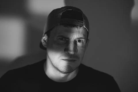 Young man in a baseball cap posing for a portrait. Dramatic lighting with s.. Stock Photos