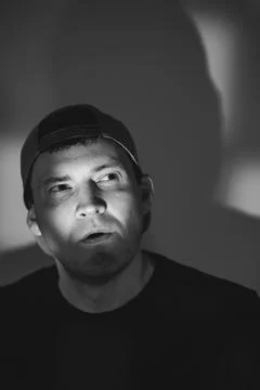 Young man in a baseball cap posing for a portrait. Dramatic lighting with s.. Stock Photos