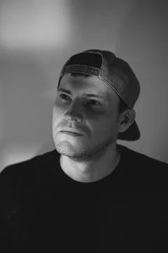 Young man in a baseball cap posing for a portrait. Dramatic lighting with s.. Stock Photos