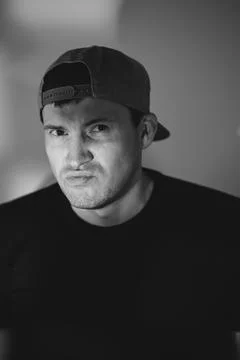 Young man in a baseball cap posing for a portrait. Dramatic lighting with s.. Stock Photos