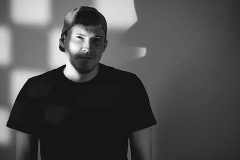 Young man in a baseball cap posing for a portrait. Dramatic lighting with s.. Stock Photos