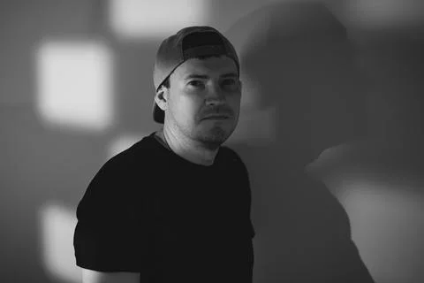Young man in a baseball cap posing for a portrait. Dramatic lighting with s.. Stock Photos