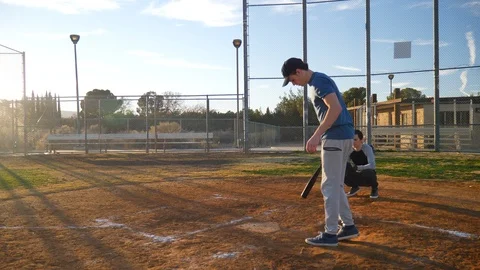 A young man baseball player swings his bat in slow motion and misses the Stock Footage 100689152
