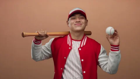 Young man in baseball uniform holding bat and ball confidently against isol.. Stock Footage 313459732