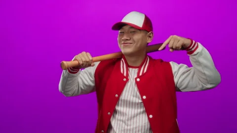 Young man in a baseball uniform points down while holding a baseball bat ov.. Stock Footage 309883962