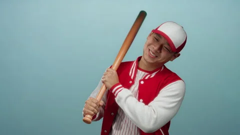 Young man in baseball uniform smiles with bat against isolated blue backgro.. Stock Footage 311936002