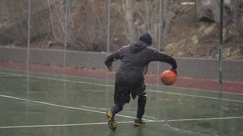 A young man basketball player practicing his ball handling outdoors in the freez Stock Footage 71167141