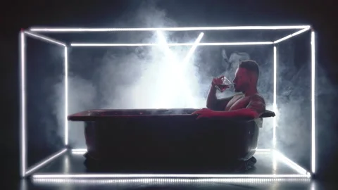 Young man in the bath drinks a drink and pours himself Stock Footage 147633059