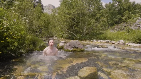 Young man bathing in water of mountain river at hot summer day Stock Footage 94244418
