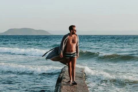 Young man in a bathrobe on the beach in sunset Stock Photos