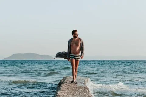 Young man in a bathrobe on the beach in sunset Stock Photos