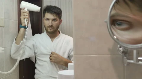 Young man in bathrobe drying his hair in bathroom Stock Footage 64766120