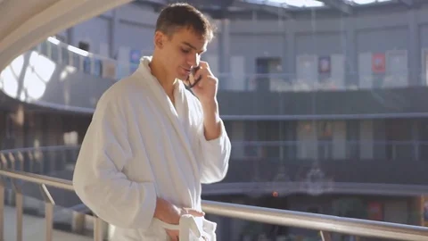 Young man in bathrobe talking on cellphone Stock Footage 83312001