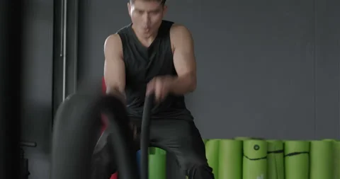 Young man battle ropes exercise in the fitness gym, Powerful guy using ropes dur Video stock 137005272
