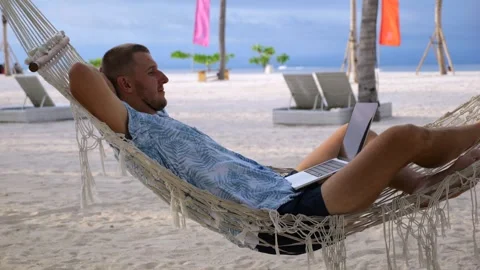 Young man on beach. Close-up: man in hammock on beach near ocean, puts his hands Video stock 270006809