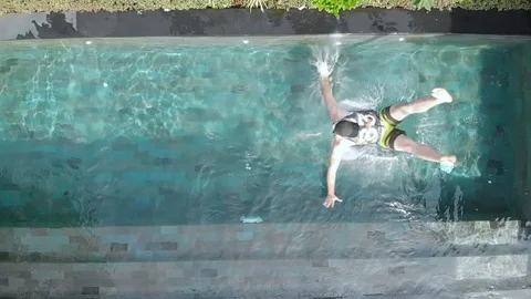 A young man in beach clothes falls into the pool. Slow motion. Stock Footage 103963772
