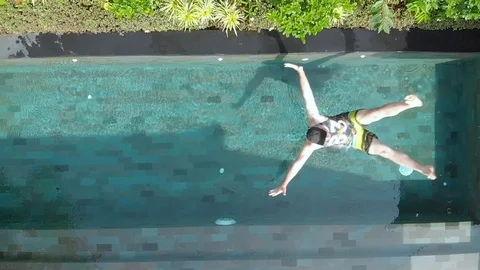 A young man in beach clothes falls into the pool. Stock Footage 103963879