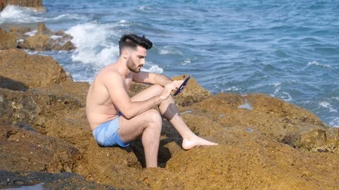 Young man on beach reading with ebook reader Stock Footage 91152966