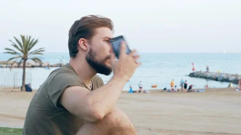Young man on beach talking on smartphone Stock Footage 118935191