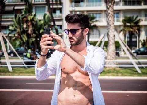 Young man on beach using cell phone to film the sea Foto stock