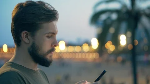 Young man on beach using smartphone Stock Footage 118938817