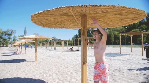 A young man on the beach waving someone's hand Stock Footage 76303661