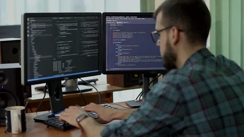 A young man with a beard and glasses works behind a computer Stock Footage 71666047