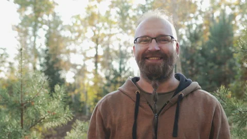 A young man with a beard and glasses smiles and rejoices at the camera on the 動画素材 99628457