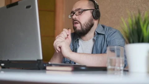 Young man with a beard and glasses using a laptop with headphones. Stock Footage 164895711