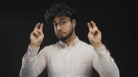 Young man with beard and glasses making air quotes gesture against a black .. Stock Footage 311501433