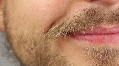 Young man with beard and mustache smiles, half front view, lips macro closeup Stockbeeldmateriaal 93209857