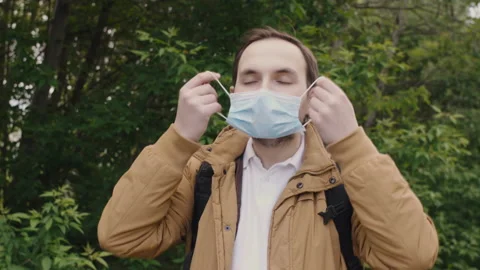 A young man with a beard and mustache gladly removes a protective medical mask Video stock 135420481