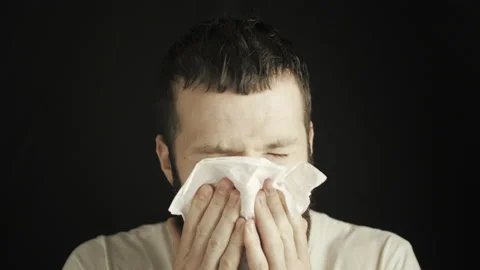 A young man with a beard and mustache blows his nose into a handkerchief Stock Footage 138998734