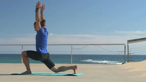 Young man with beard and ponytail performing stretching exercises by the se.. Stock Footage 229727661