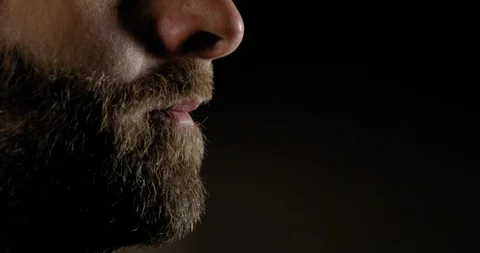Young Man with a Beard Blows a Whistle in front of a Black Background  Видео 129332044