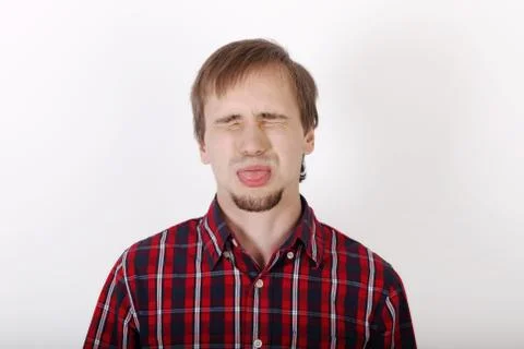 Young man with beard in checkered red shirt dabbles and shows tongue Stock Photos