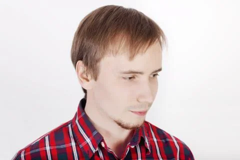 Young man with beard in checkered red shirt thinks and looks away Stock Photos