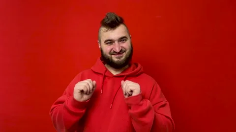 Young man with beard dances on red background Stock Footage 272769579