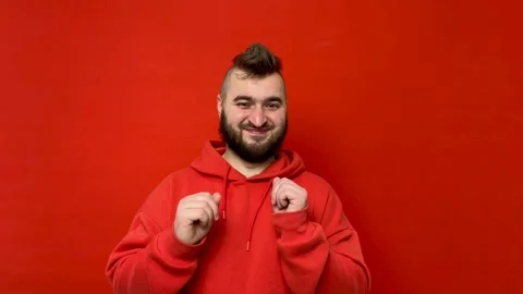 Young man with beard dances on red background Stock Footage 276561428