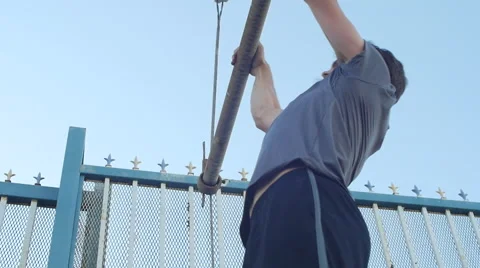 A young man with a beard doing pull-ups in urban environment, slow motion. 動画素材 68537146